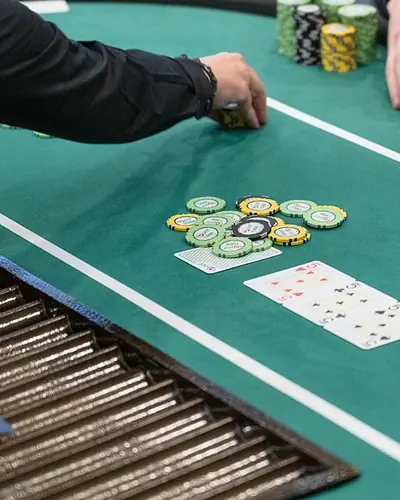 Mani del croupier al tavolo da gioco con fiches e carte
